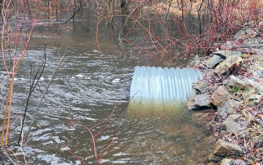 A galvanized steel culvert inundated with flood waters.